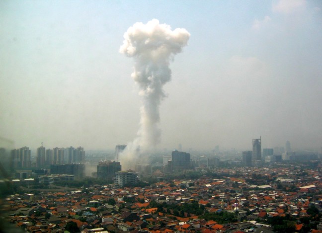 A large plume of smoke shoots into the air from the Jakarta city skyline. 