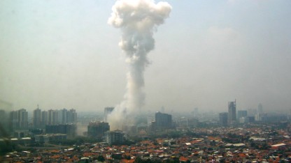 A large plume of smoke shoots into the air from the Jakarta city skyline. 